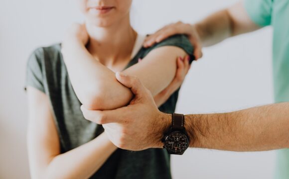 Doctor examining a female patient's elbow and arm for pain
